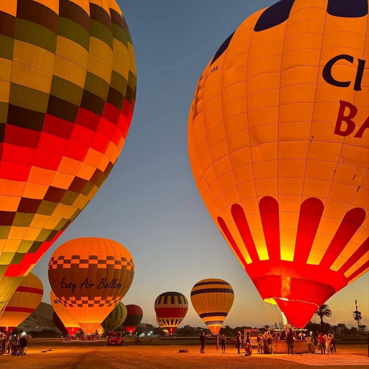 Balloons lit by their burners at the launch field before dawn