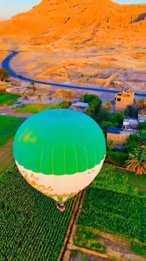 Balloon floating over green fields below the West Bank cliffs